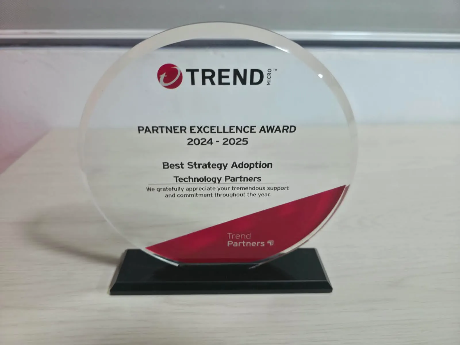 Galardón circular Partner Excellence Award 2024 - 2025 sobre base negra, con la inscripción Best Strategy Adoption a nombre de Technology Partners y la marca Trend Micro.